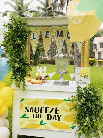 A "Squeeze the Day" lemonade cart, complete with a beverage dispenser and fresh greenery.