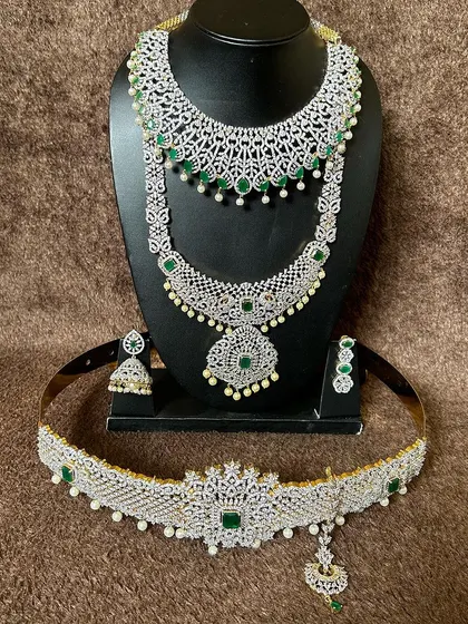 A complete CZ stone bridal set with emerald-green stones. This rental package includes a choker, long necklace, and a matching vaddanam for a coordinated look.