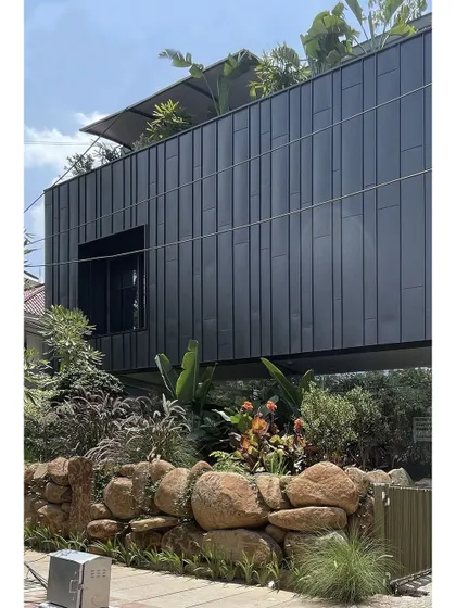The site edge of this office building is designed as a natural buffer, with a wall of boulders and dense planting. This landscape feature creates a sense of separation from the street and integrates the building into a garden-like setting.