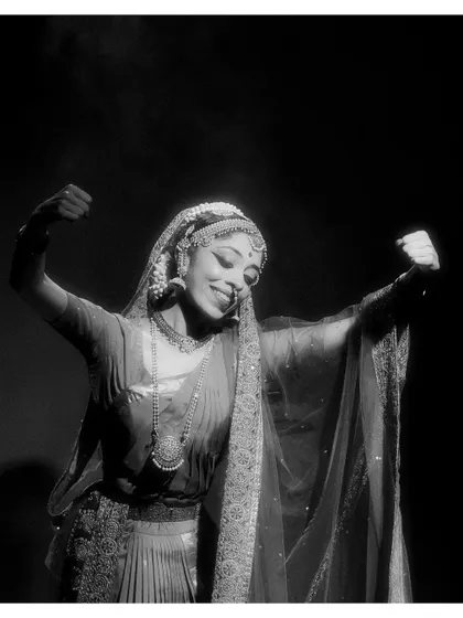 A black and white portrait of a dancer from "Tyāgarāja Hṛt Sādana," capturing her expressive smile and intricate jewelry. It highlights the beauty and detail of our performance aesthetic.