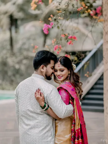 An intimate pre-wedding portrait of a couple in traditional wear. The natural outdoor setting with flowers adds a touch of romance to the shot.