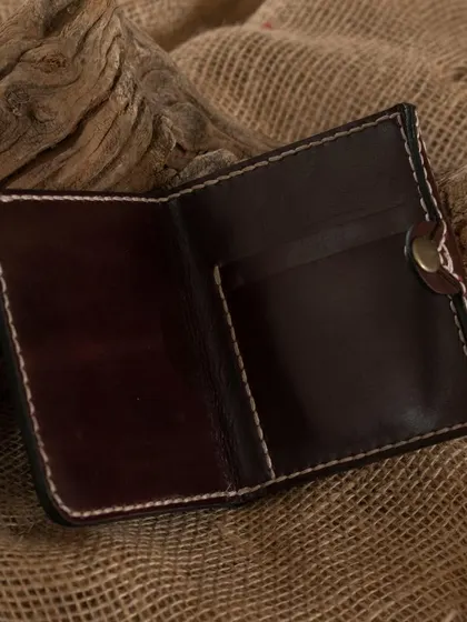 A finished leather wallet resting on a rustic background, highlighting the natural and durable quality of the materials used in our workshops.