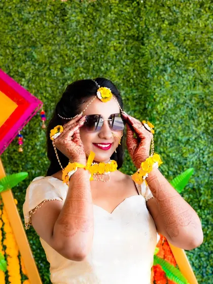 A stylish bride posing with sunglasses at her Haldi ceremony, adding a modern twist to the tradition.
