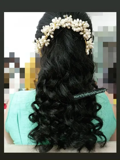 A classic half-up hairstyle with bouncy curls. The look is finished with a beautiful pearl hair accessory, making it perfect for any special occasion.