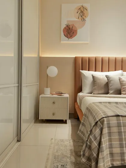 This cozy kids' bedroom uses a warm, earthy color palette of terracotta and beige. The plaid blanket and simple, modern art create a comfortable and stylish space that a child can easily grow into. The fluted headboard and nightstand add a touch of texture.