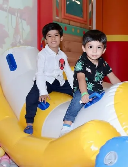 Two young friends ride together on an inflatable see-saw in the ball pit.