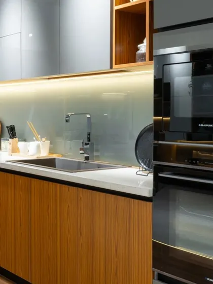 A close-up of the integrated oven and microwave tower in the wood-finish kitchen, showcasing how we seamlessly incorporate modern appliances into our designs.