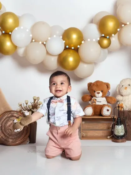 A joyful shot of a one-year-old boy kneeling and smiling in our popular bohemian-themed set.