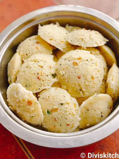 A bowl of hot and savory Rava Idly, a popular breakfast item for events. We make them fresh to order, seasoned with mustard seeds, curry leaves, and mild spices.