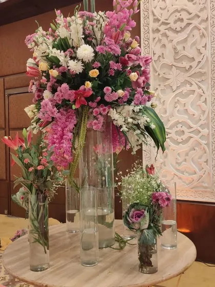 A beautiful and tall floral centerpiece for a guest table or entrance lobby. This arrangement uses a mix of lilies, carnations, and chrysanthemums in tall glass vases for a dramatic effect.