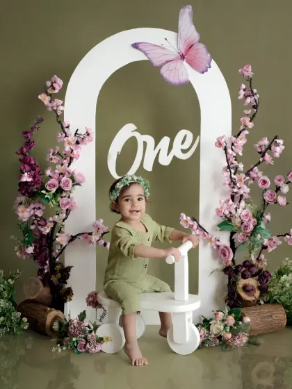 A whimsical first birthday shoot with a butterfly and floral arch theme. The soft green and pink tones create a gentle, enchanting atmosphere for your little one.