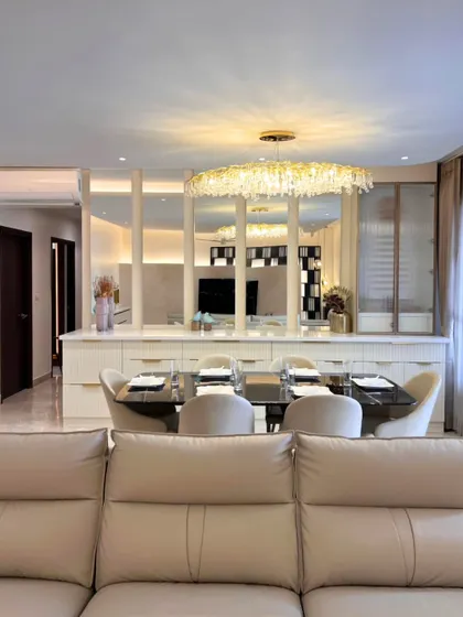 This dining space is defined by a stunning crystal chandelier that adds a touch of sparkle. Mirrored panels behind the console reflect light and create an illusion of spaciousness, making the area feel both glamorous and open.