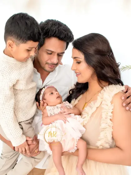 A heartwarming portrait of a family of four. The older brother looks lovingly at his new baby sister, a precious moment captured forever.