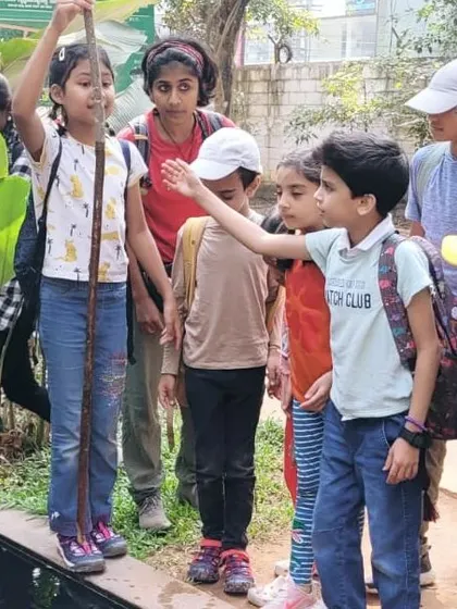 A child uses a measuring stick to check the water level, a simple yet effective way to learn about measurement and the water cycle.