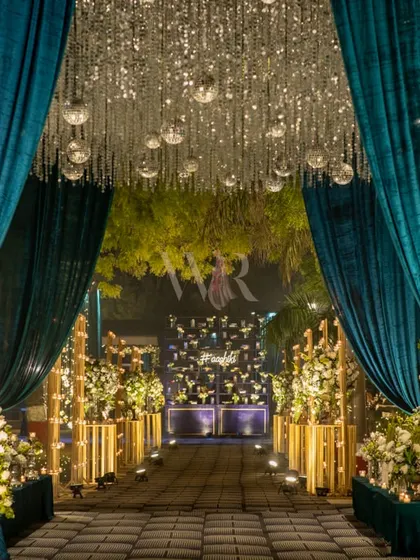 The grand entrance to the sangeet. Guests walked through heavy teal velvet drapes, under a ceiling of hanging disco balls and crystals, into a space designed for celebration.