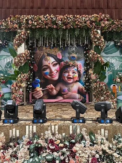 The full stage setup for the Krishna-themed baby shower, complete with peacock props and floral arrangements.
