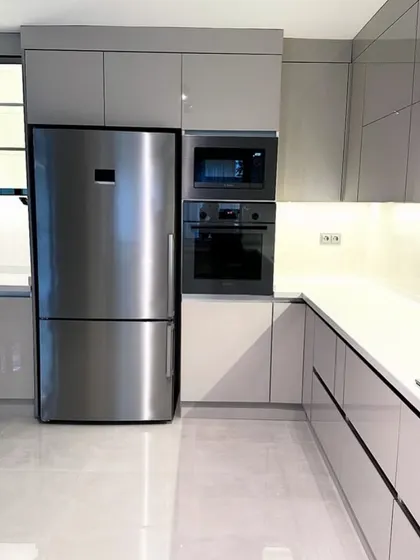 We design for complete functionality. This view shows the tall unit housing a built-in oven, microwave, and a side-by-side refrigerator, all perfectly integrated within the sleek, uniform cabinetry for a clean, uncluttered look.