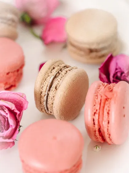 A close-up composition of different colored macarons and rose petals, showcasing variety and texture.