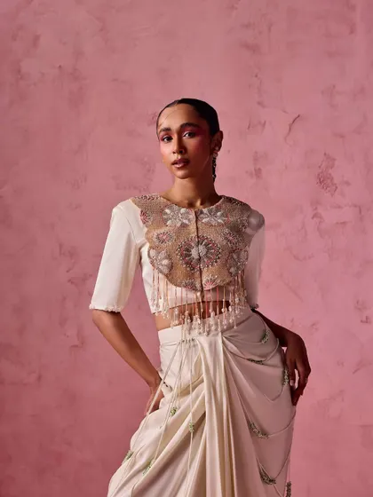 A stunning example of a modern reception outfit. The embellished crop top is paired with a draped skirt and chains, creating a look that is glamorous, edgy, and sophisticated.
