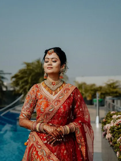 A serene moment by the pool. The bride, with her eyes closed and a gentle smile, basks in the sunlight, creating a peaceful and beautiful portrait.