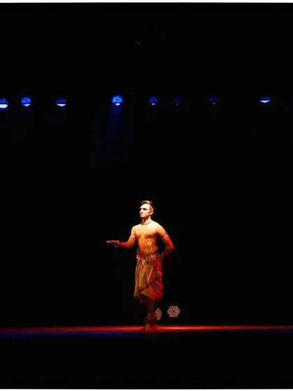 A wide shot of me on stage during a solo performance. The vast, dark stage emphasizes the solitary nature of the recital, creating an intimate connection with the audience.