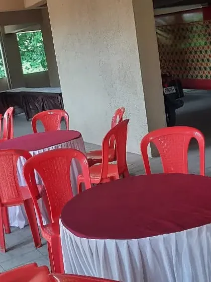 Round tables with covers and red plastic chairs set up in a building's parking area. I can turn unconventional spaces into functional event venues.