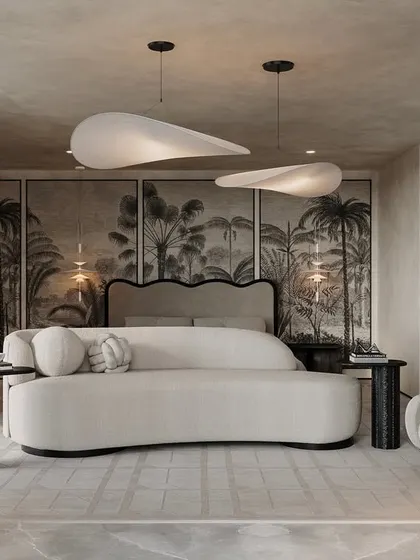 Concrete textures and neutral upholstery with soft, curved lines are the recipe for a perfect ambiance. This bedroom sitting area, with its tropical mural and ethereal pendant lights, feels like a breezy, understated retreat.
