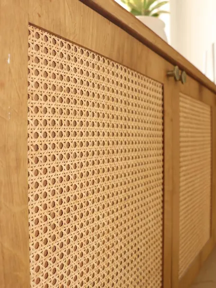 A closer look at the cane and wood cabinet. The natural texture of the woven cane provides a beautiful contrast to the smooth wood frame, showcasing our attention to material details.