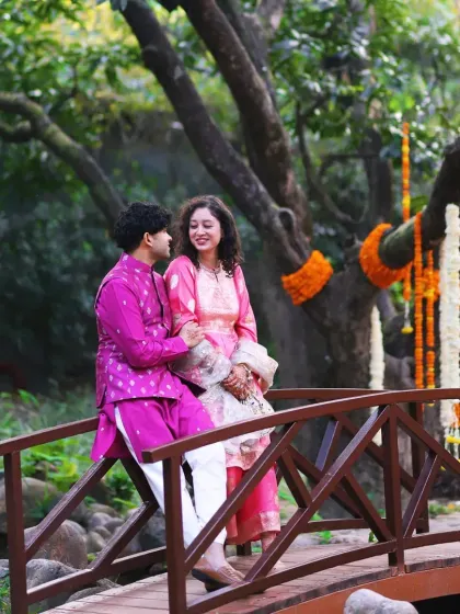 A couple enjoys a quiet moment on a rustic wooden bridge during their Mehendi celebration at Taj Corbett.