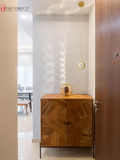 A beautiful shot of the minimalist foyer with the geometric wood cabinet, showing how the pendant light creates a captivating pattern on the wall.