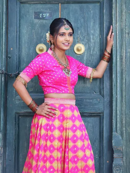 A model in a bright pink lehenga, wearing our oxidized silver-finish necklace for a vibrant, festive look.