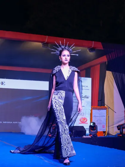 A model presents a unique design with a sheer cape and patterned trousers on the Memorabilia runway.