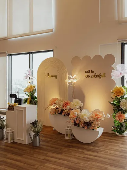 A minimalist and modern floral setup for Aanay's first birthday. The clean lines of the arched backdrops are softened by beautiful, oversized paper flowers and warm lighting.