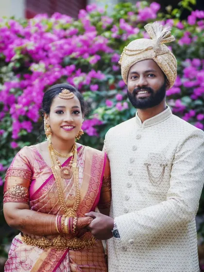 A classic wedding portrait of the couple holding hands, set against a vibrant floral background.