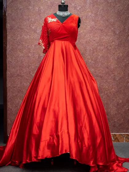 A vibrant red gown with an asymmetrical embroidered sleeve. This bold and beautiful dress is designed to make a statement at any event.