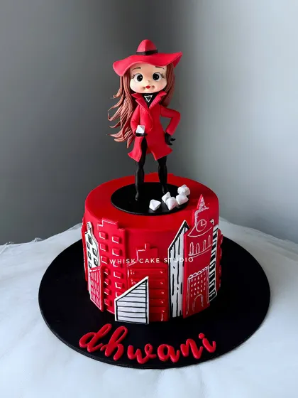 A Carmen Sandiego themed cake for a little adventurer. This striking red and black cake features a cityscape design and a handcrafted figurine of the iconic character.