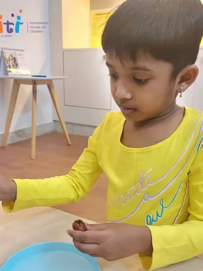 A student carefully fills a date with a sweet mixture. This task requires precision and focus, key skills developed through Montessori practical life exercises.