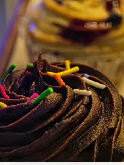 A slightly different take on the chocolate cupcake, with a blueberry muffin in the background. The focus remains on the detailed frosting, showing how I can create a series of related but unique shots.