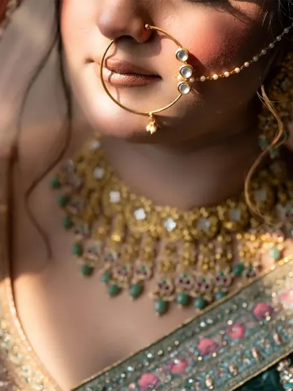A close-up shot of the bride's nath and necklace, capturing the intricate details of her wedding jewelry in soft, natural light.