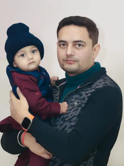 A father and his baby, dressed warmly for a winter event, pose for a portrait.