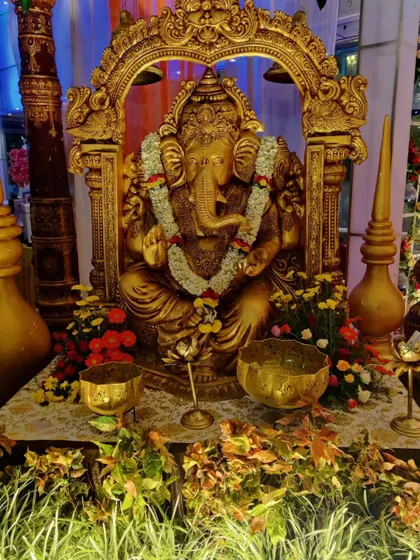 A slightly different angle of the golden Ganesha statue, highlighting the intricate details of the idol and the surrounding floral decor.