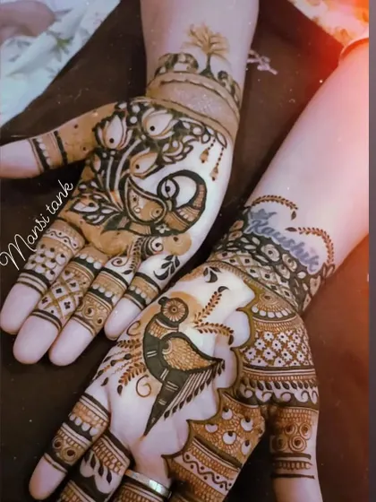 This design showcases a love for peacocks, with different styles of the bird on each palm. One hand also includes a name written in a heart.