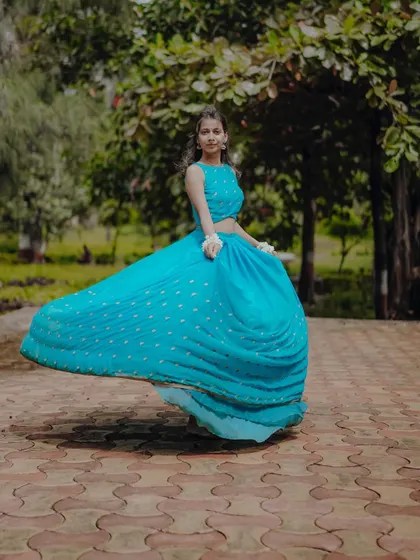 A dynamic shot capturing the joyful twirl of a flowing blue lehenga, embodying the spirit of Radha in a garden setting.