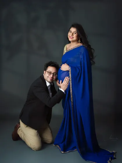 A classic and heartwarming pose. The dad-to-be kneels to listen to the baby's heartbeat, a moment of pure love and anticipation.