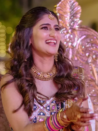 Bride Sneha looking joyful at her sangeet. We built her look around an heirloom gold set, pairing it with a colorful and traditional lehenga by Mayyur Girotra.