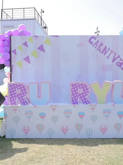 A personalized backdrop for twins "Ru & Ryu" at their outdoor carnival party. The setup includes life-sized animal props and large, decorated letters, creating a perfect photo wall.