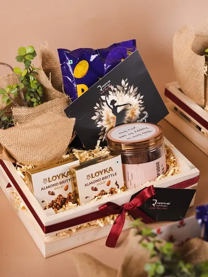 A beautiful pinewood tray hamper curated for our long-time client, Raphe. This gift includes a live plant, almond brittle, and other treats to celebrate the women on their team.