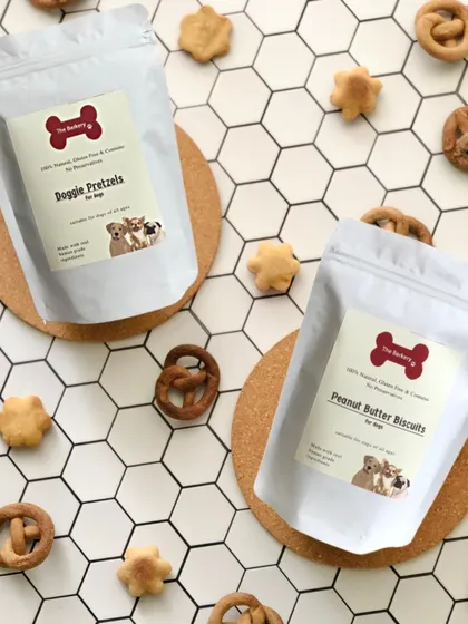 A beautiful flat lay of my Doggie Pretzels and Peanut Butter Biscuits. These treats are scattered on a clean, modern background, showing off their handmade quality and wholesome appeal.