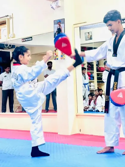 A young student practices her kicks on a target, building confidence and skill.