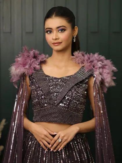 A full view of this unique and dramatic cocktail ensemble. The bold purple eye makeup perfectly picks up the tones in the feathered shoulders of her outfit.